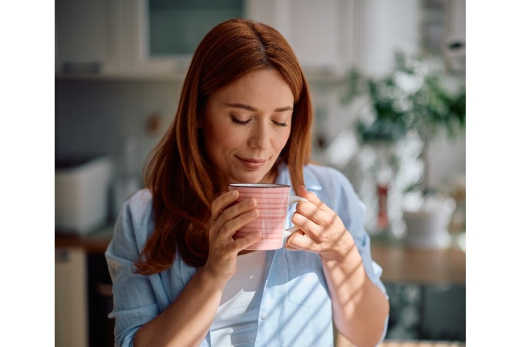 Tazza di tè verde su un tavolo di legno con foglie fresche.